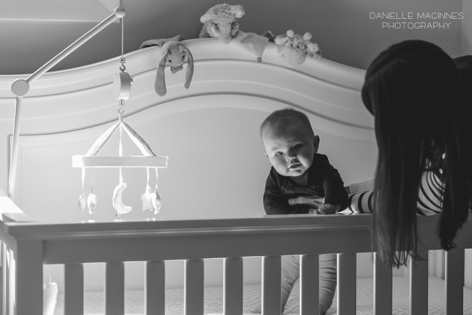 mom helping baby stand up in crib