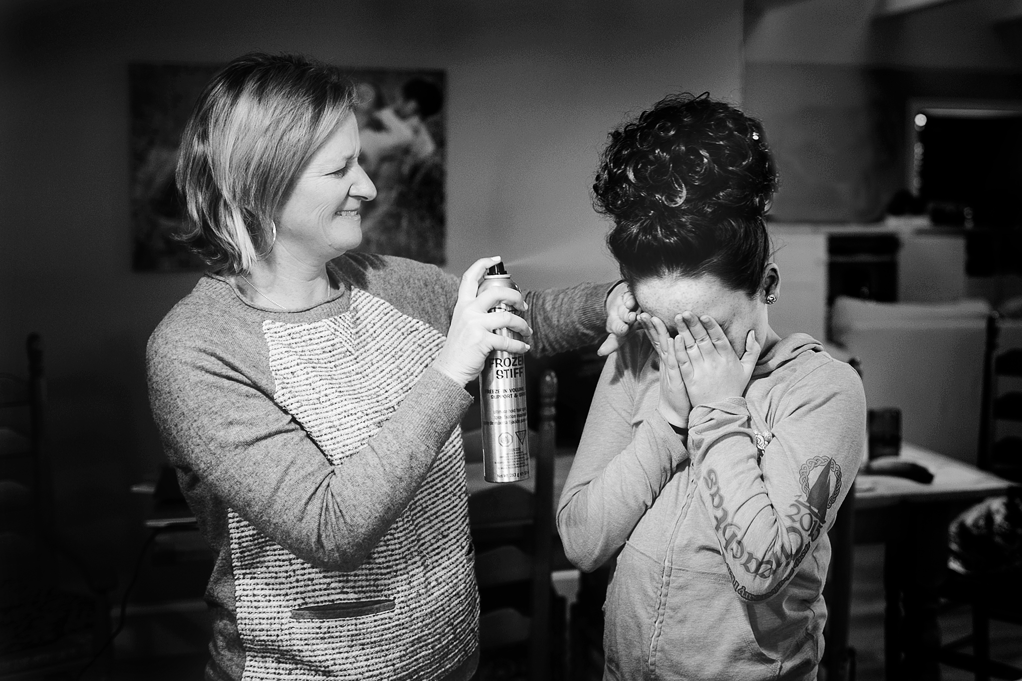 mom spraying hair spray on little girl's hair