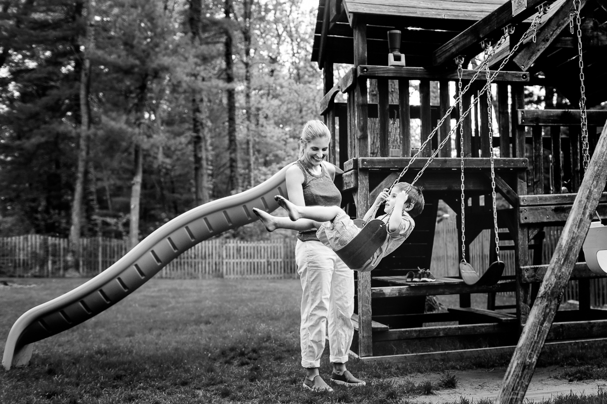 mom smiling at son on swing with barefeet