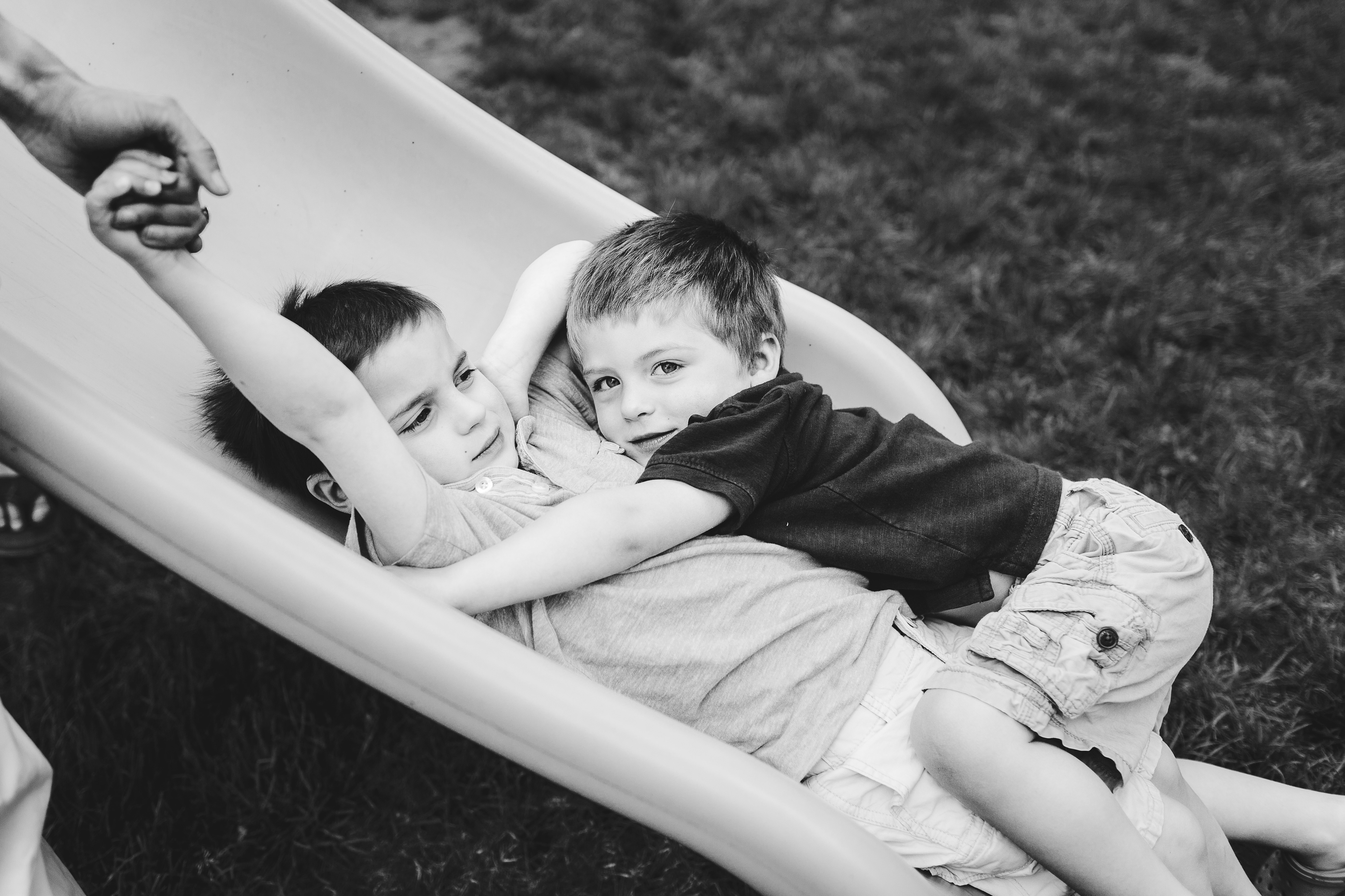 brothers hugging on slide one holding dad's hand