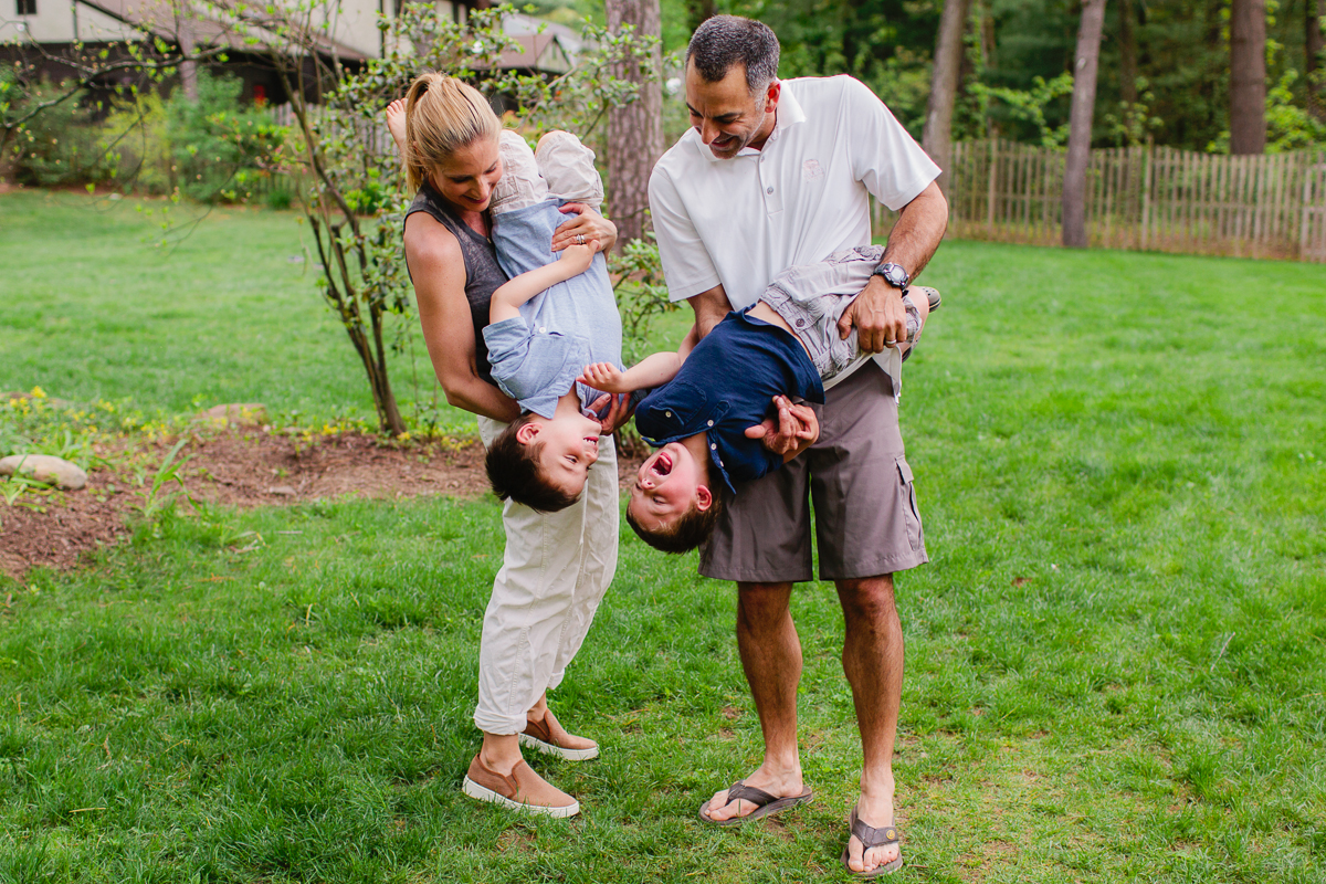 parents holding little boys upside down outside
