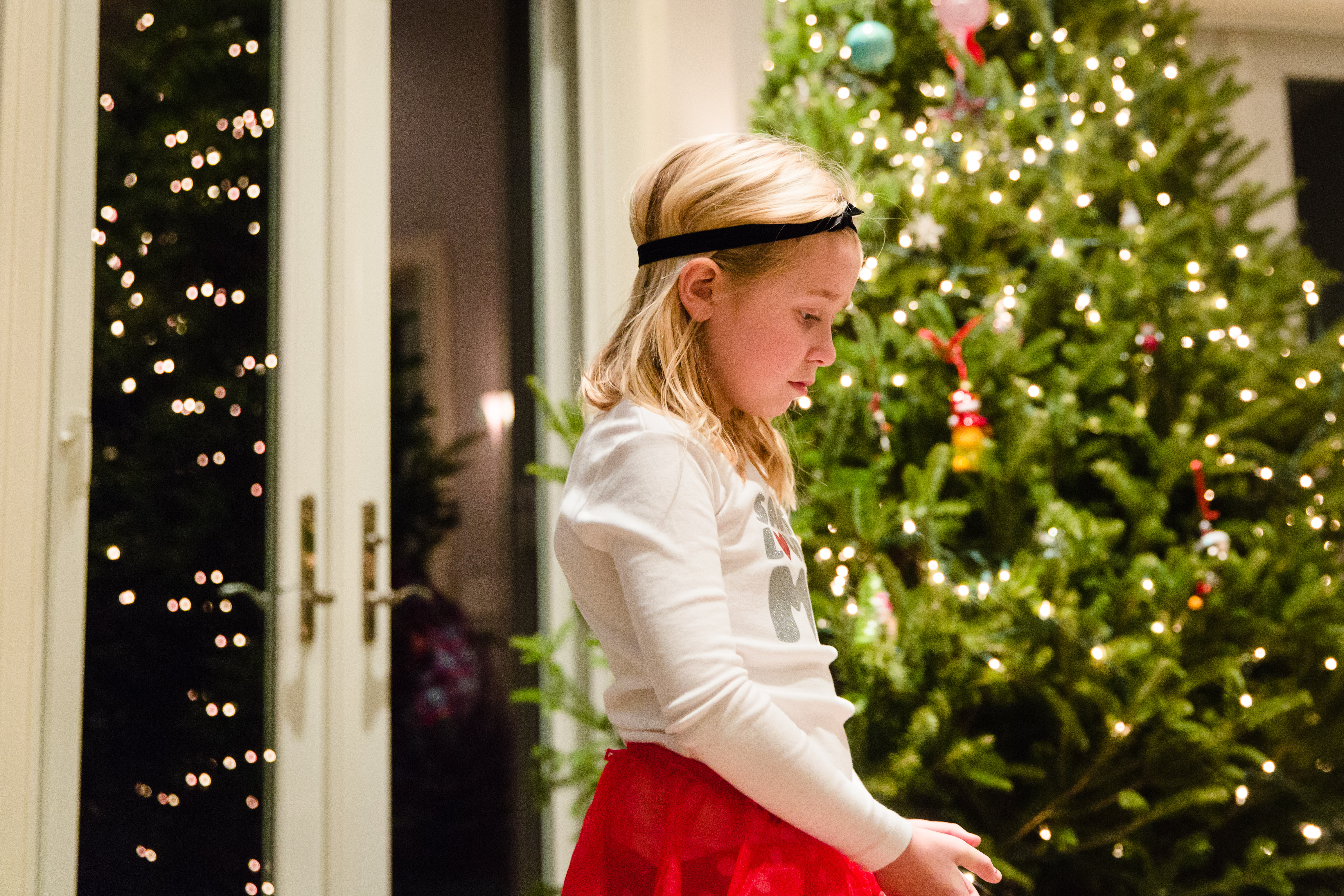 Little girl looking sad with christmas tree in background
