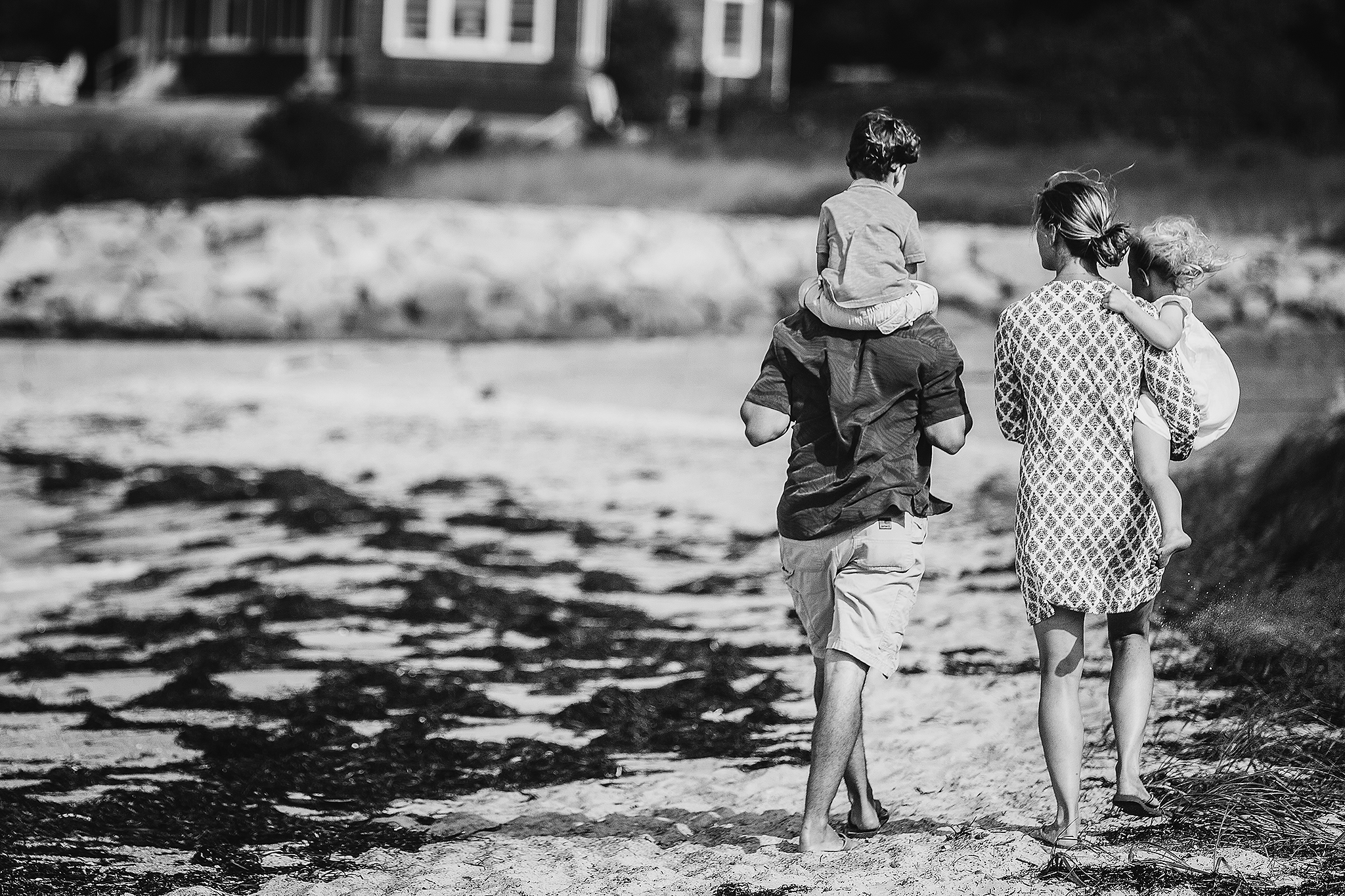 family walking on beach with boy on shoulders and girl in mom's arms