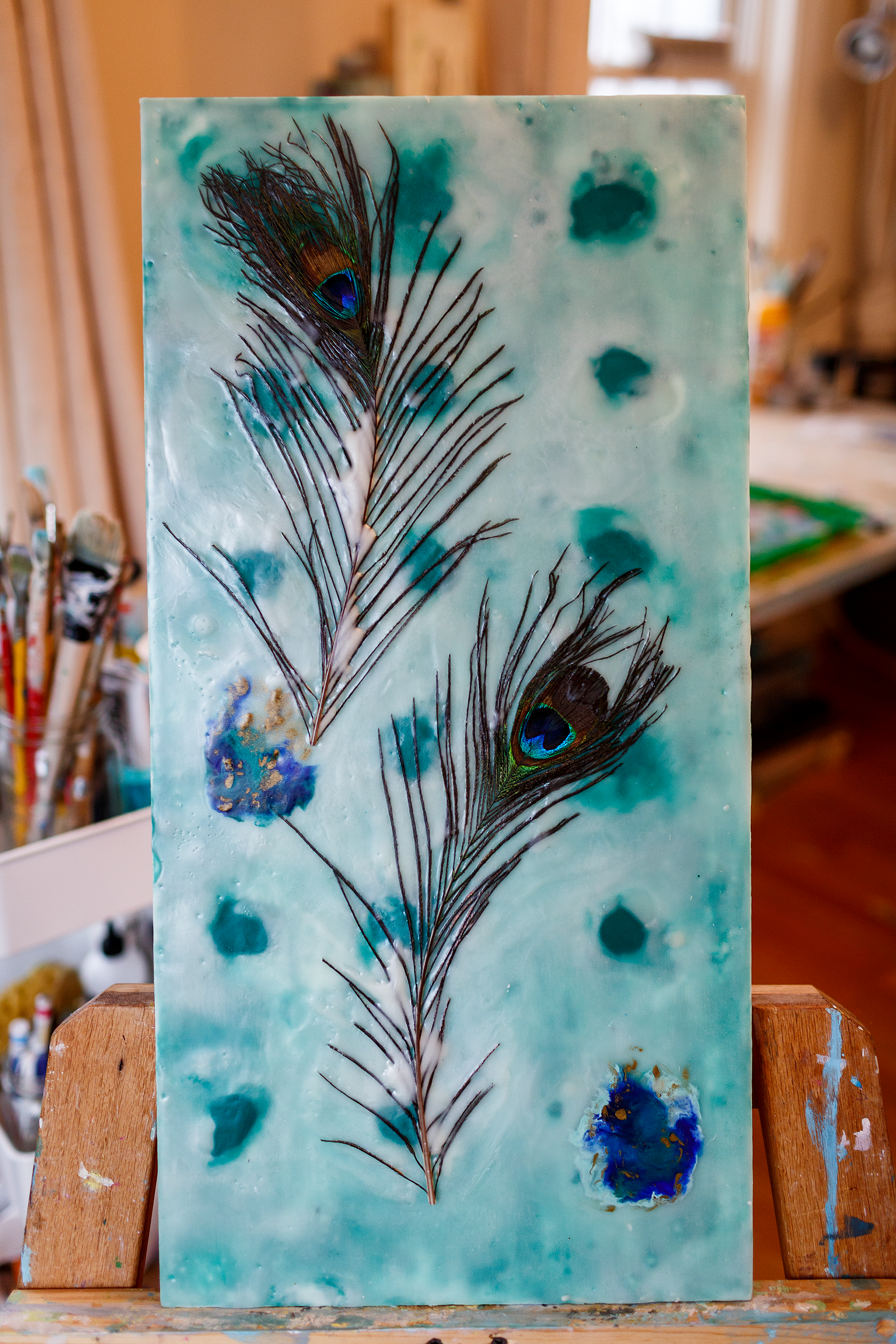 Encaustic painting of blue peacock feathers