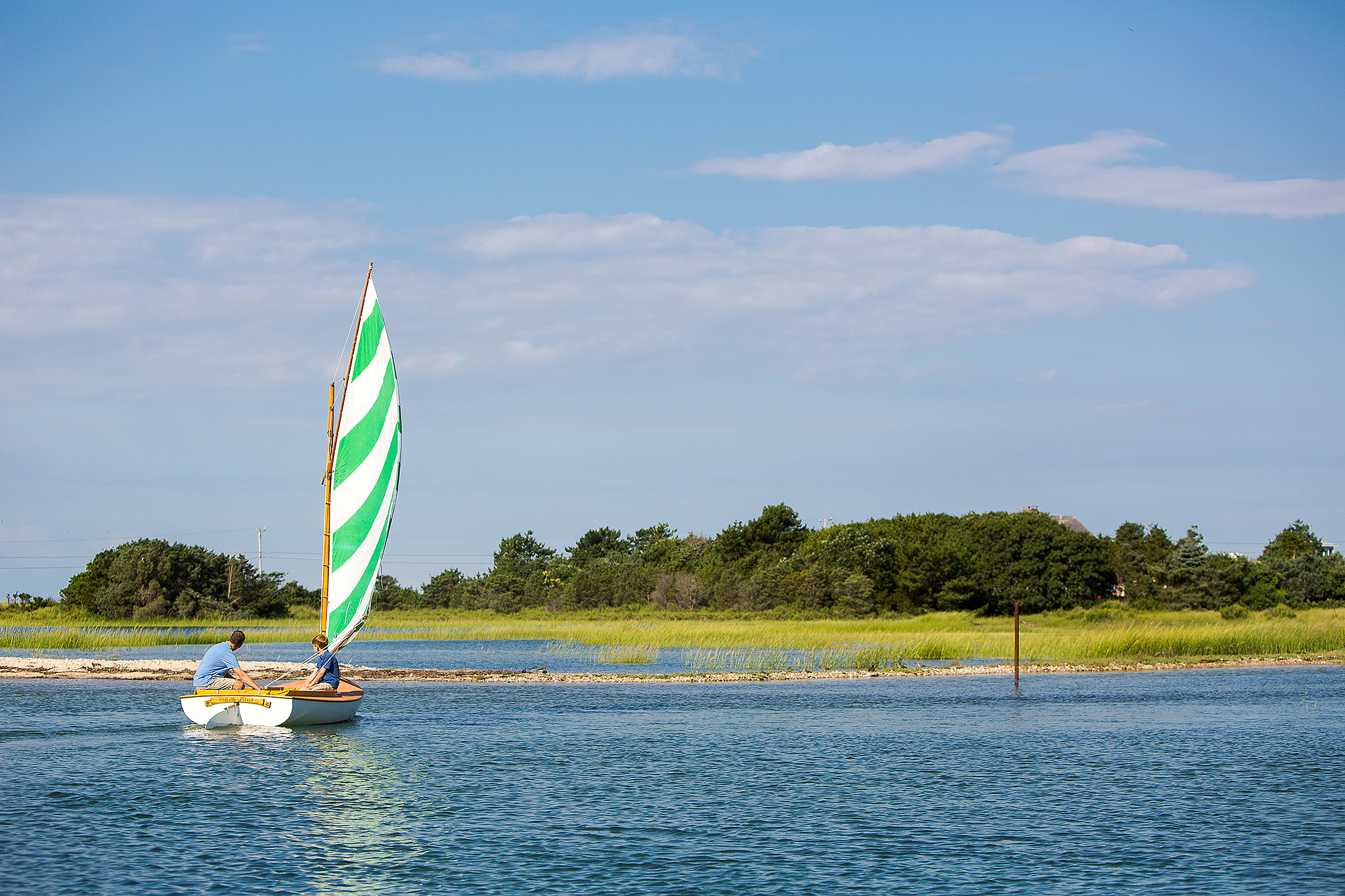 Father and son sailing in shallow water with sea grass