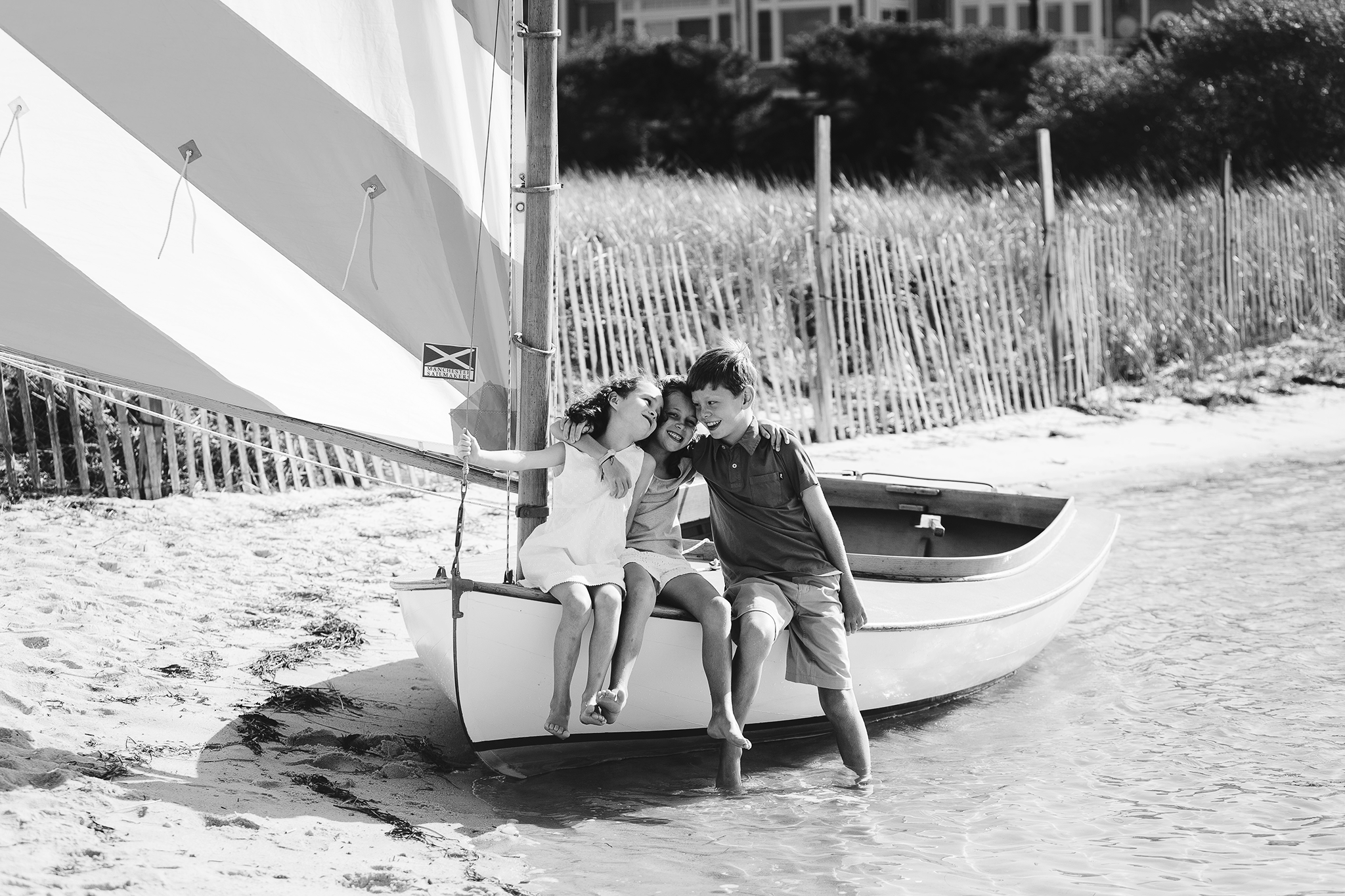 brother and sisters laughing on front of sailboat