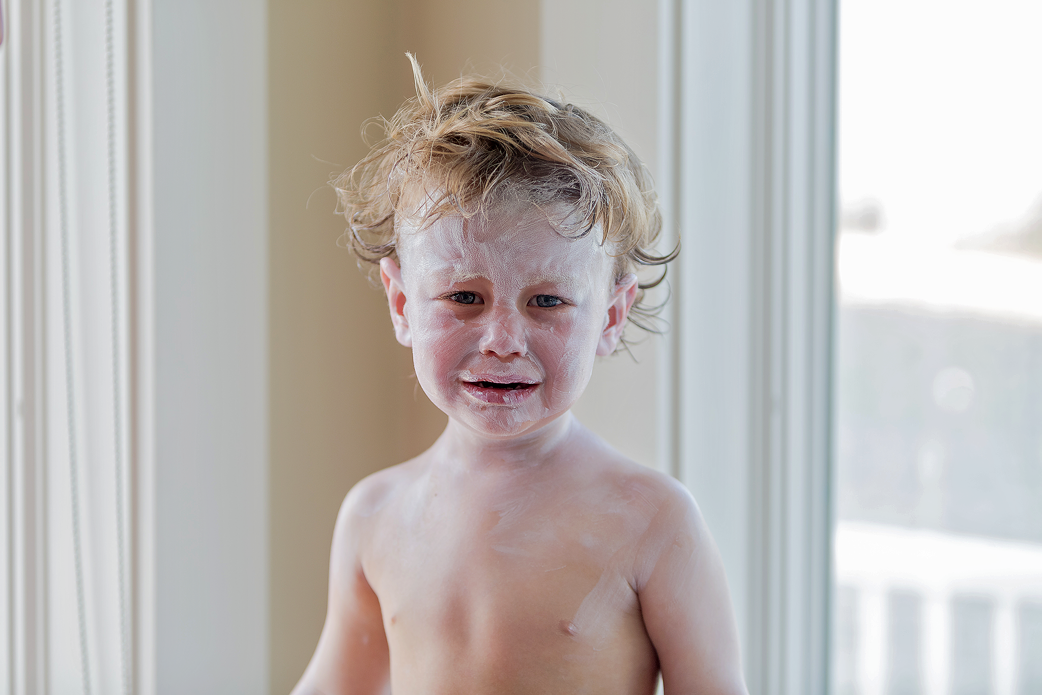 little boy crying with sunscreen on face