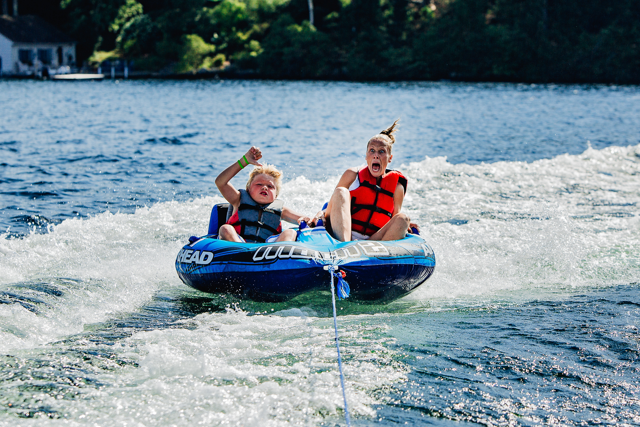 mom and son screaming while tubing on the lake