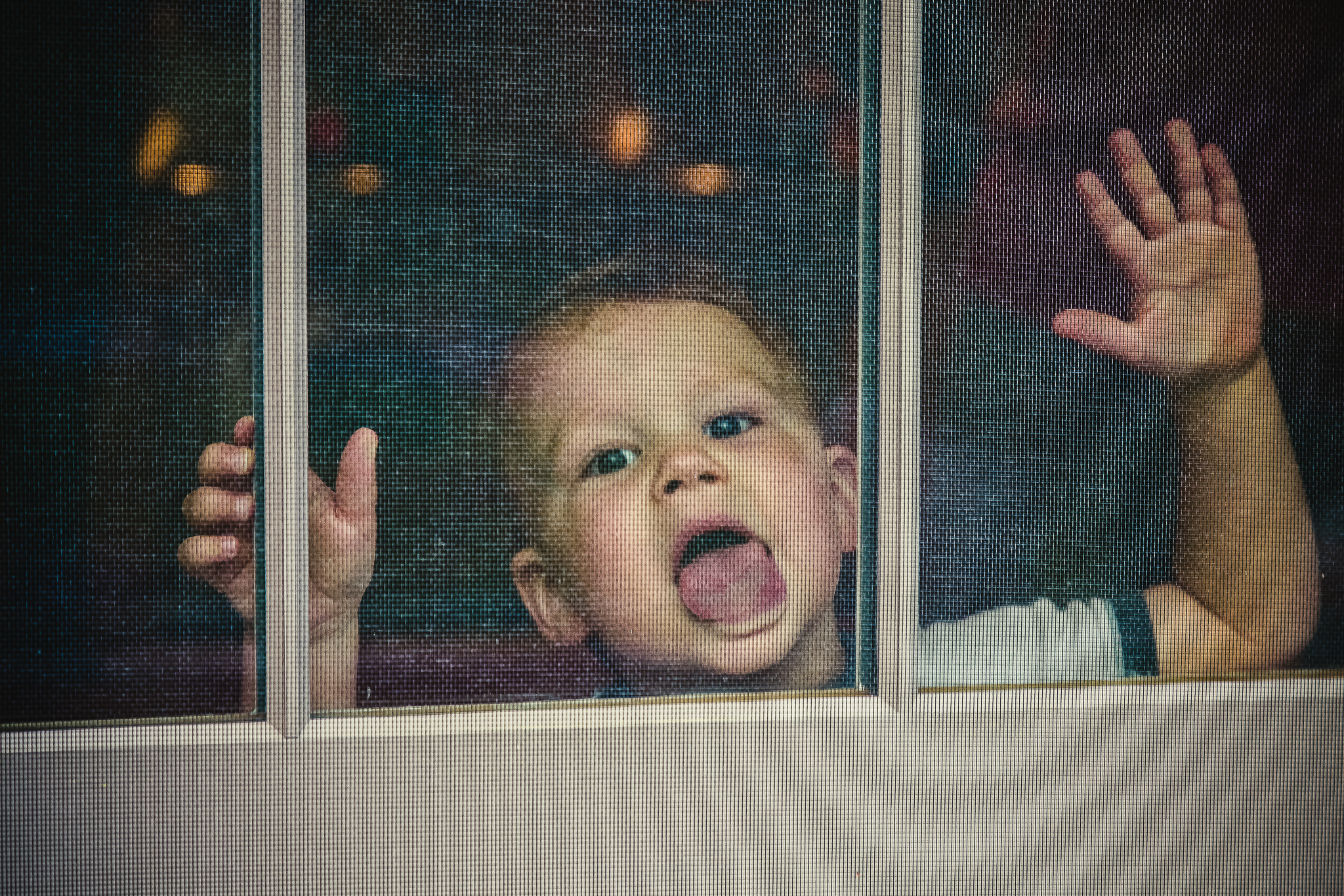 little boy licking screen window