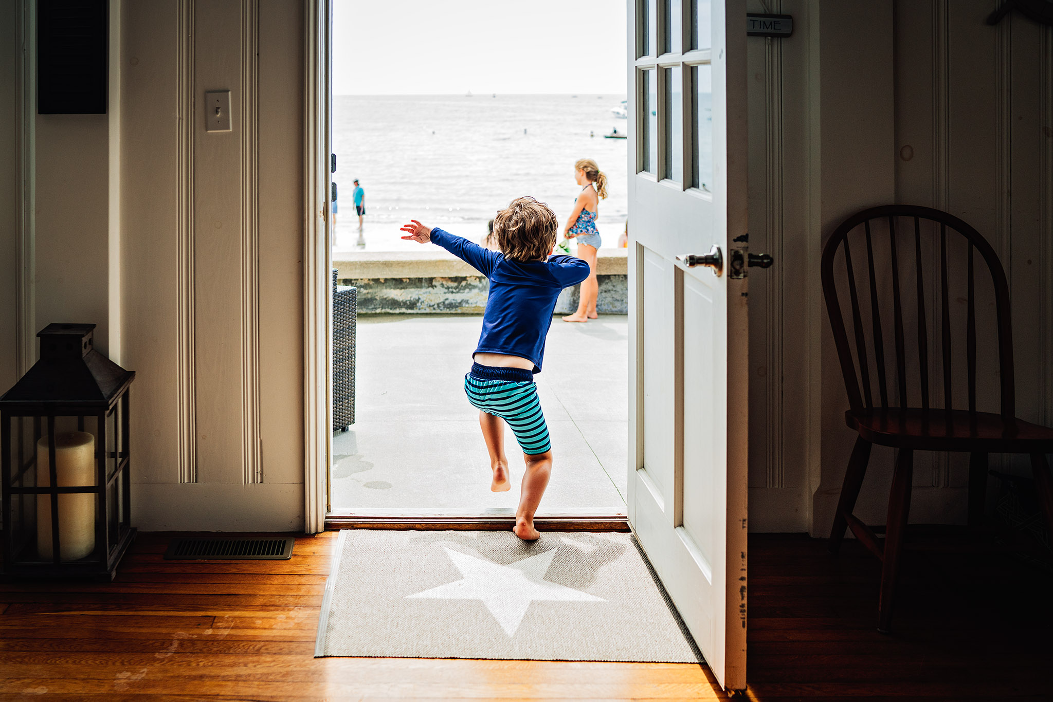 little boy in running out back door to beach