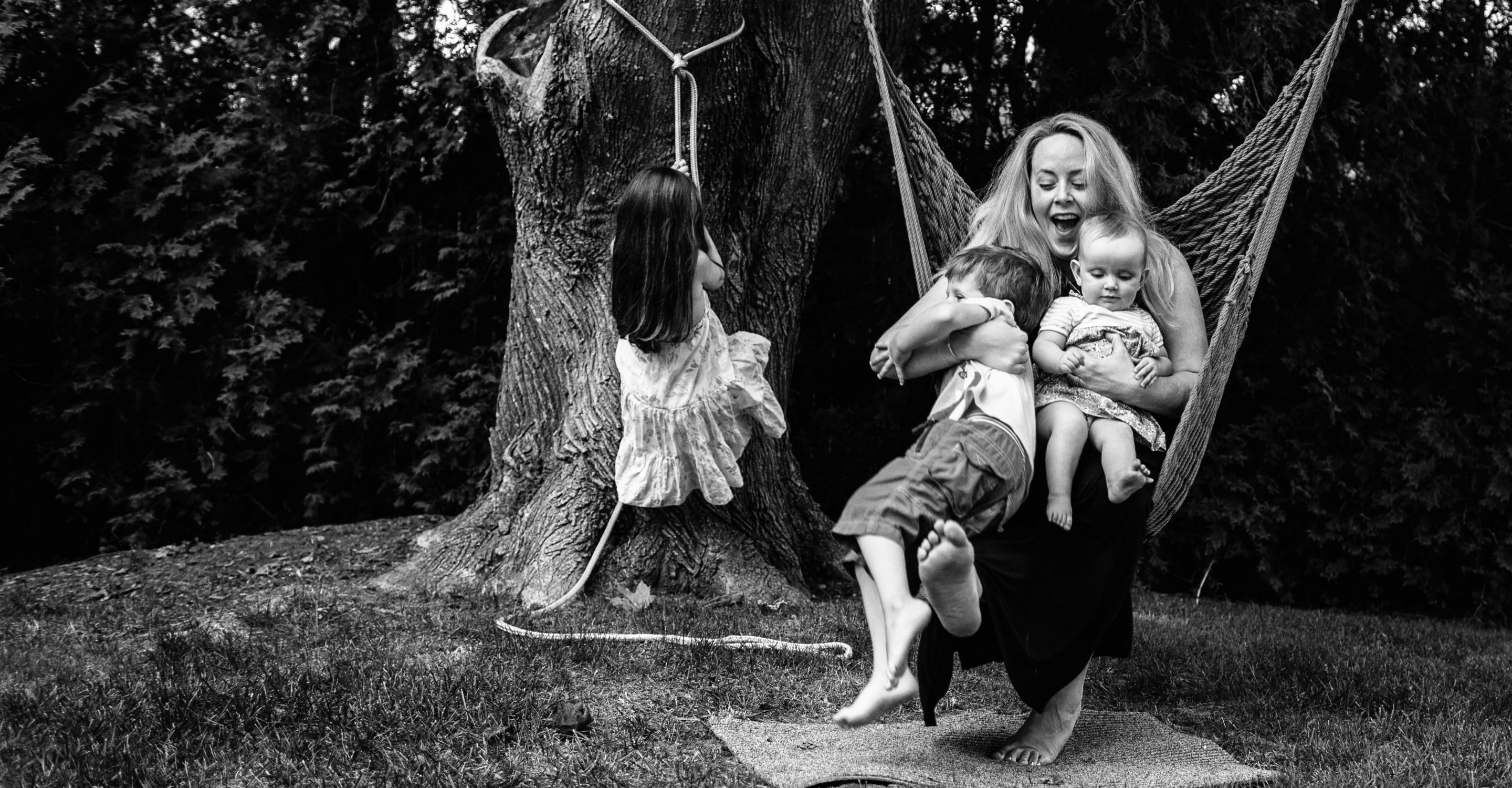 mom on rope swing with two little kids and girl climbing up tree