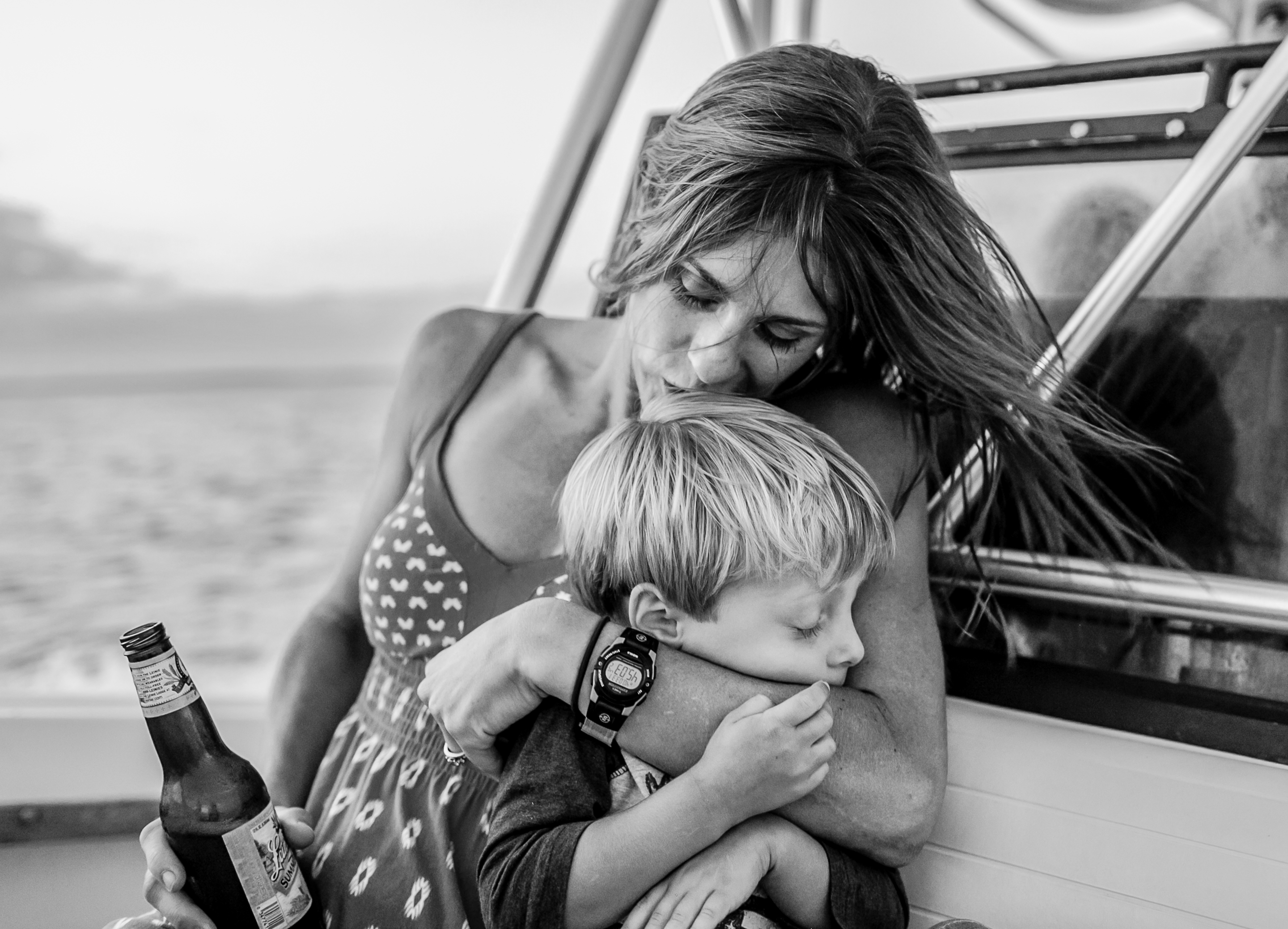 mom hugging and kissing little boy on boat