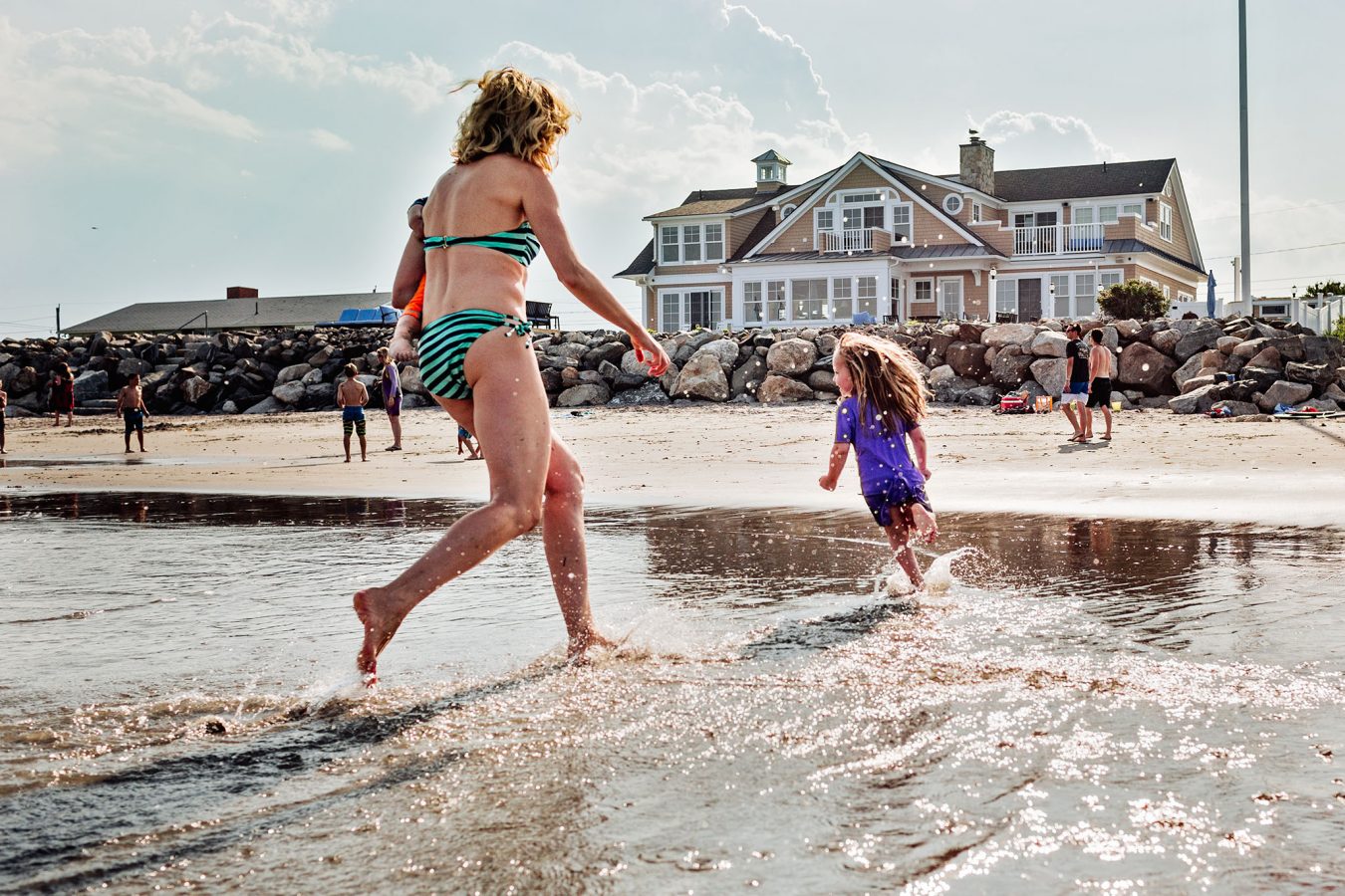 mom in bikini chasing daughter at beach