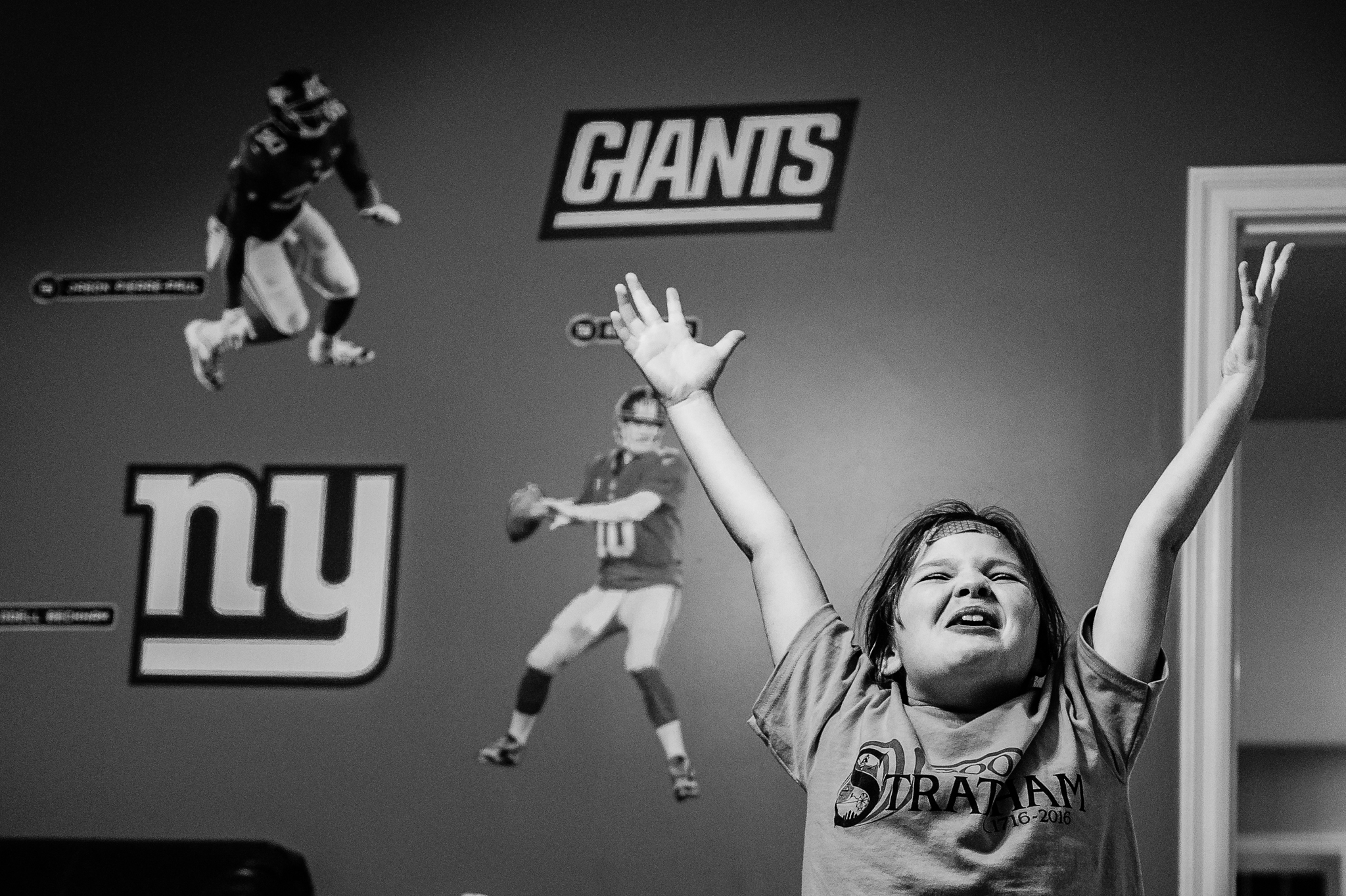 happy young girl with arms raised and giants stickers on wall