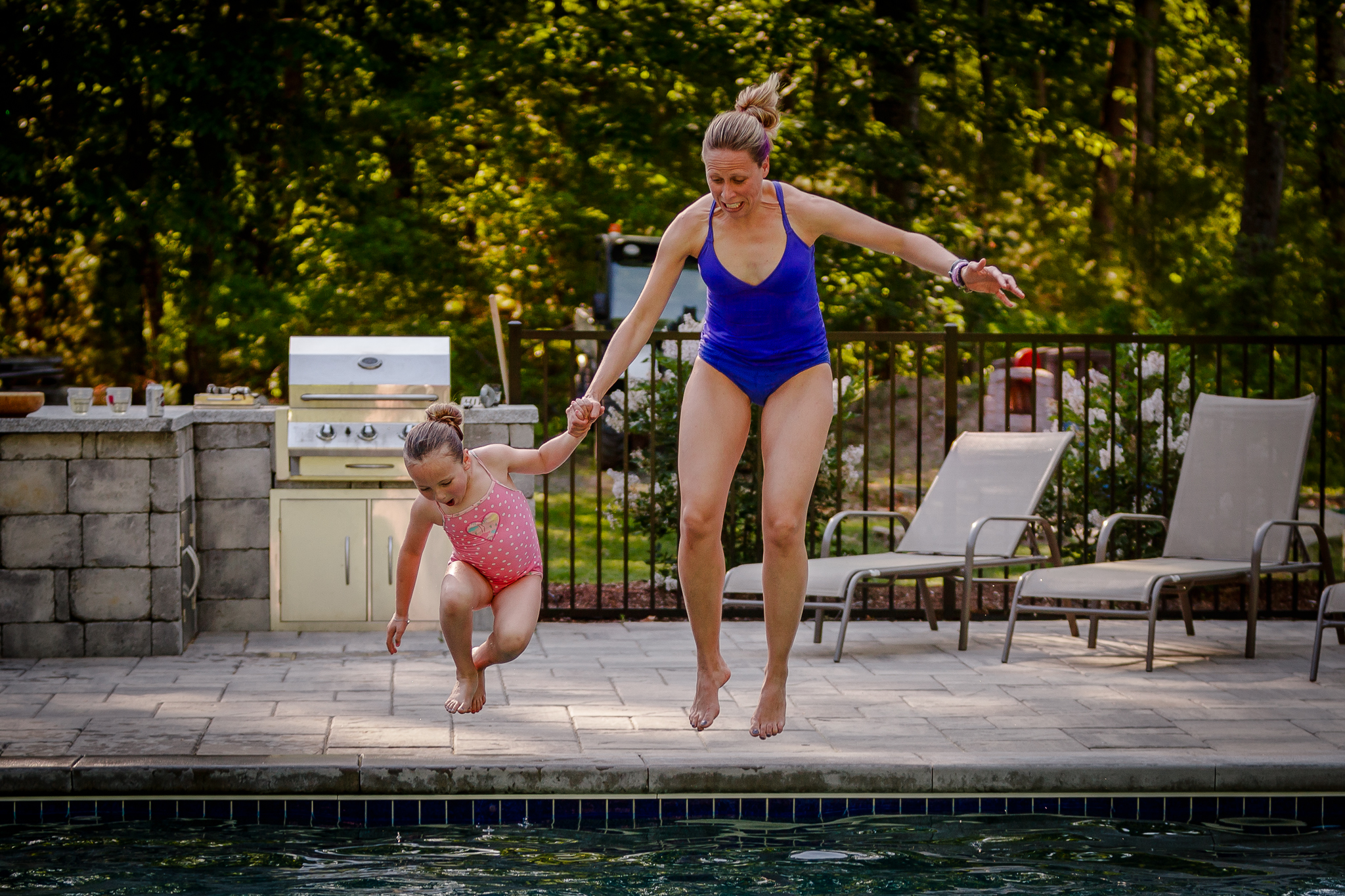 mom and daughter jumping into pool