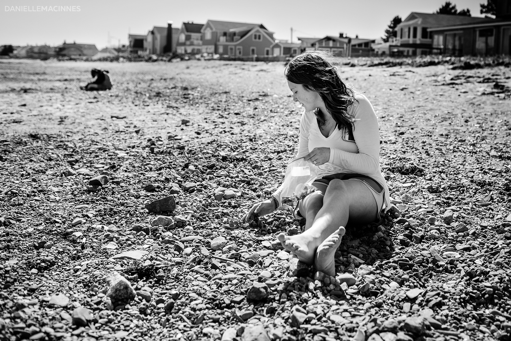 girl sitting on rocky beach looking for seaglass
