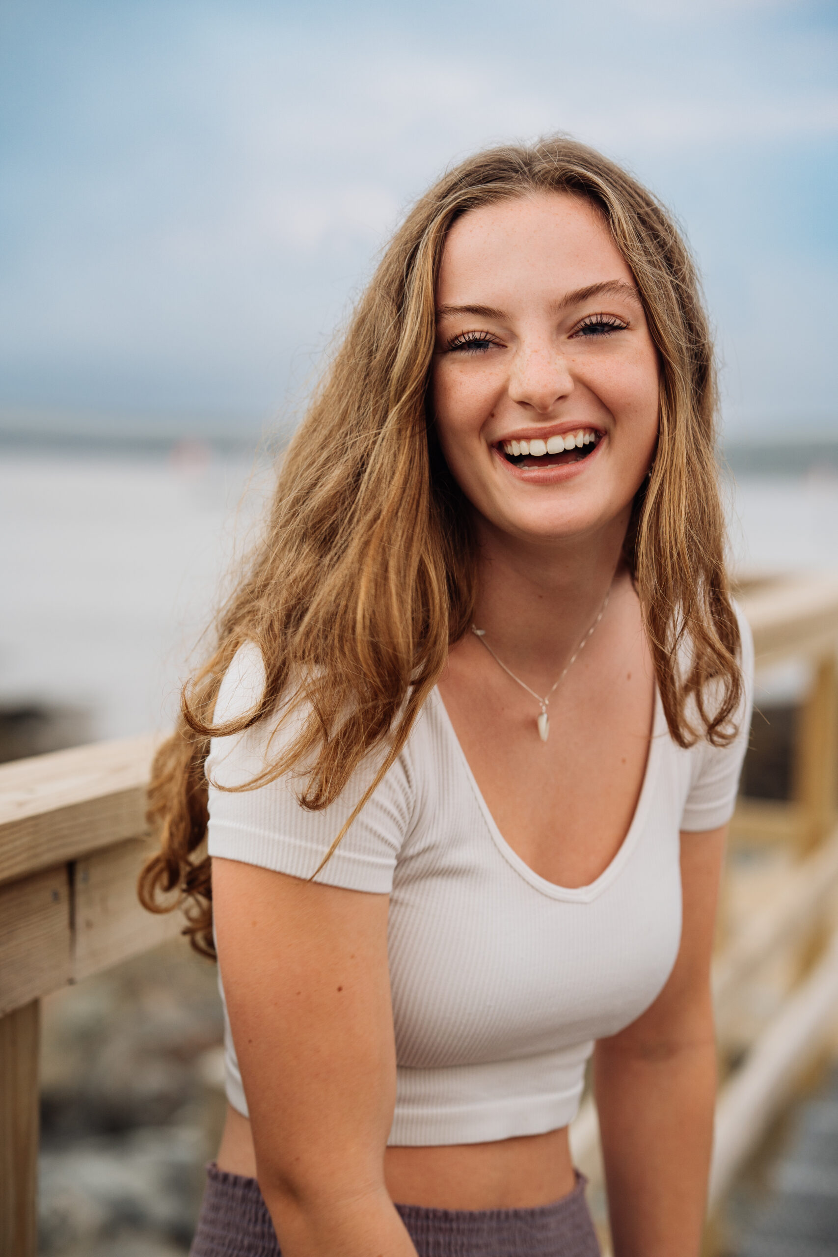 high school senior girl with brown hair laughing on a pier