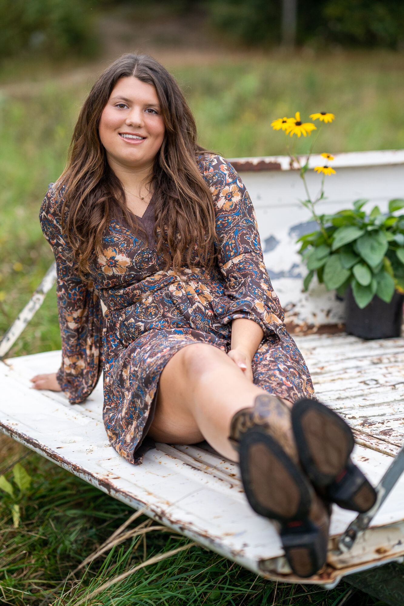 high school senior female wearing brown dress with yellow flowers sitting in back of white truck