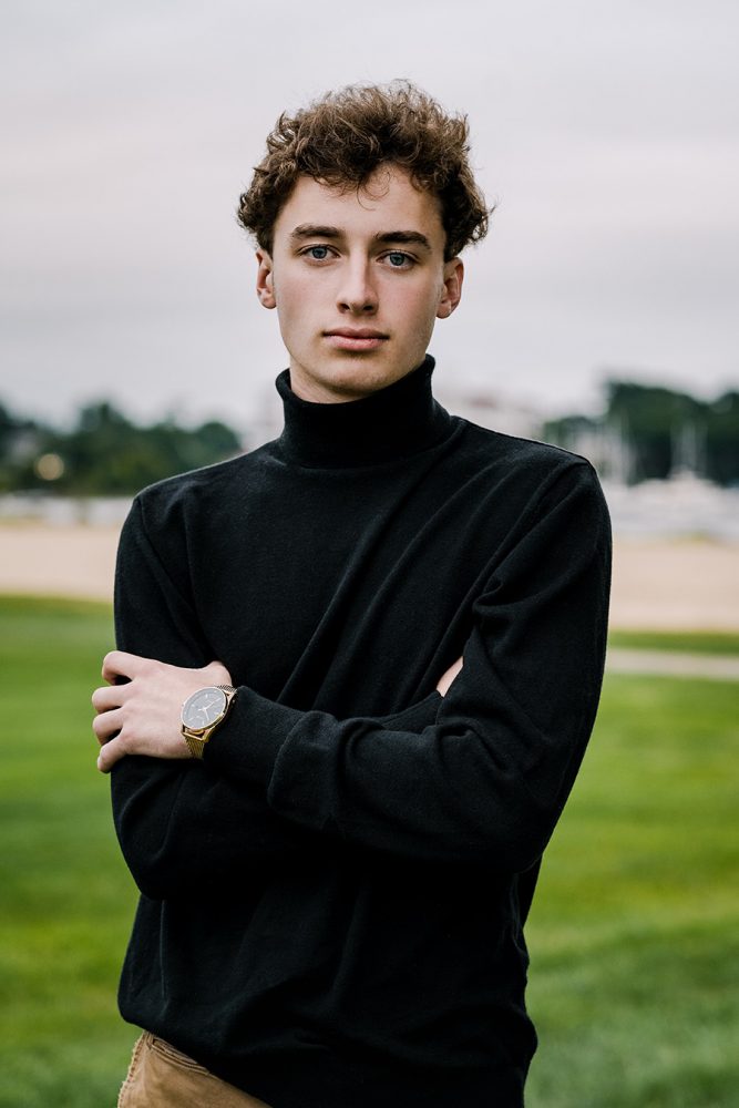 high school boy wearing black turtleneck with arms crossed not smiling