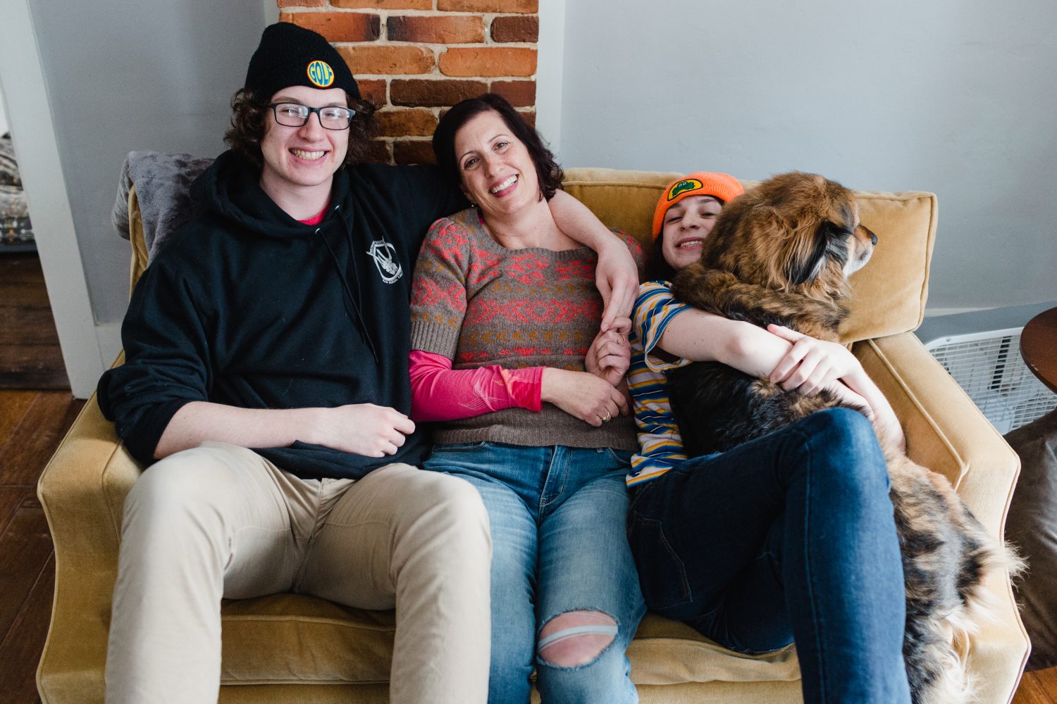 mom and teenage sons on couch with fluffy dog