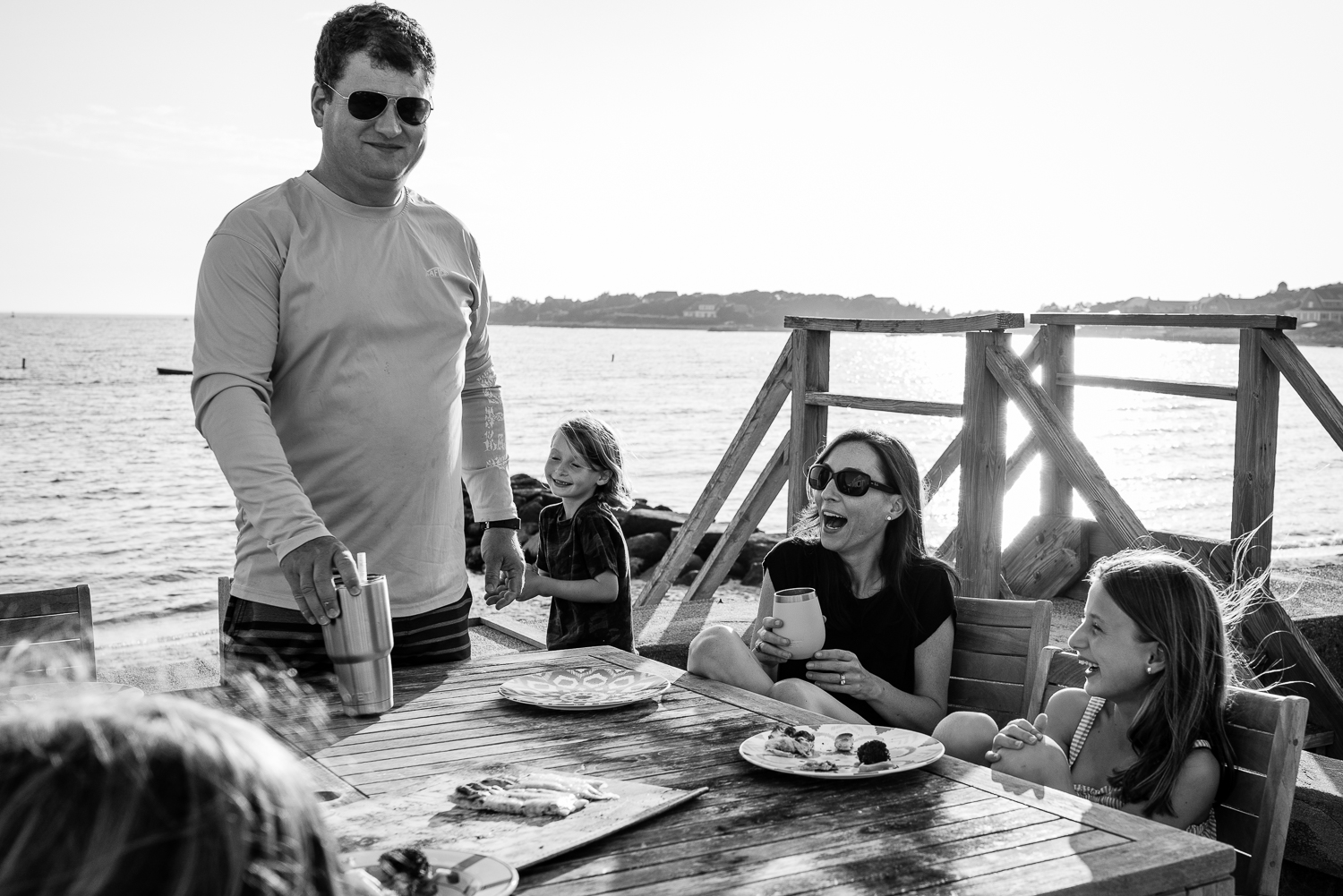 family laughing together eating outside by the ocean